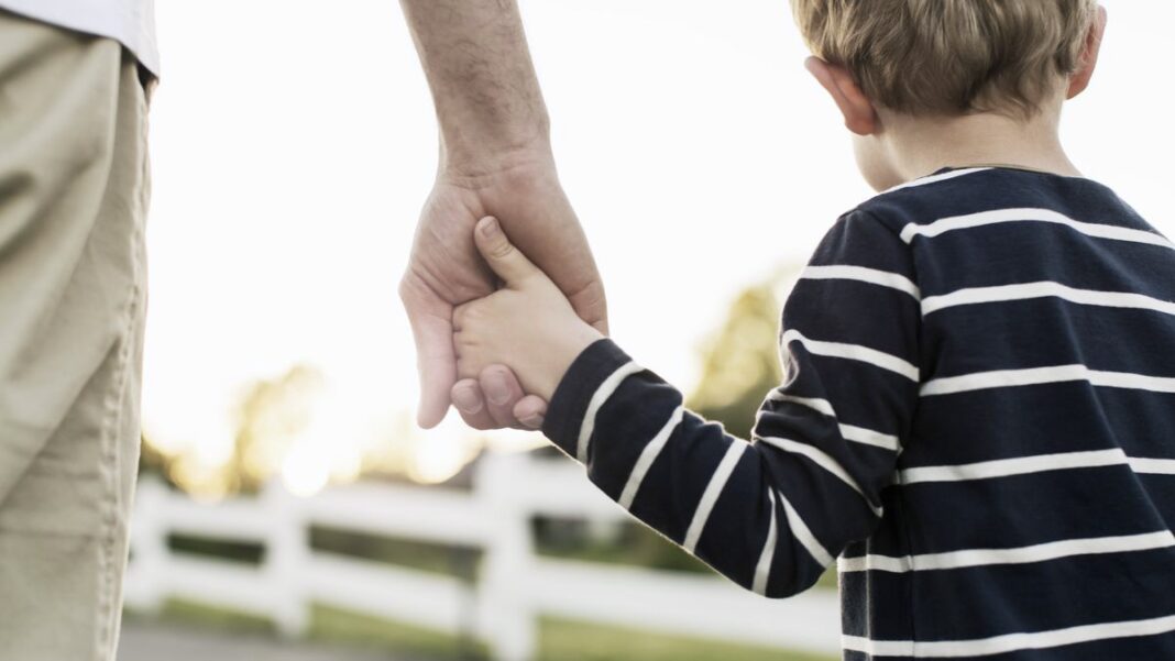 rear view of father and son holding hands while royalty free image 1661281424
