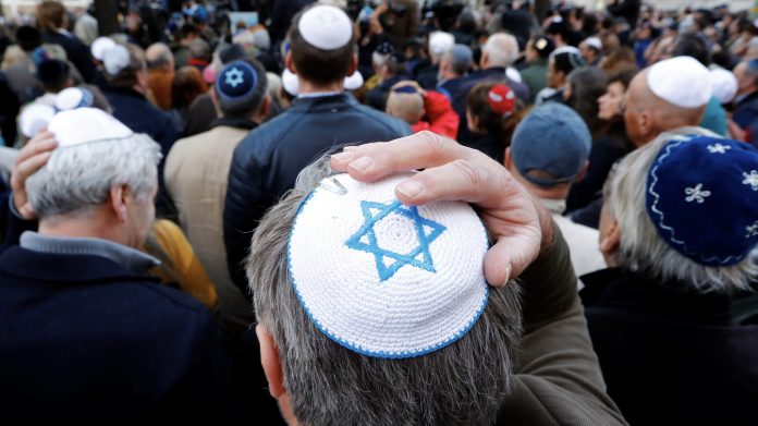 people wear kippas as they attend a demonstration in front of a jewish synagogue in berlin